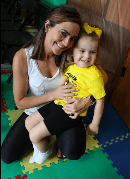 A lady with her small daughter smiling at the camera