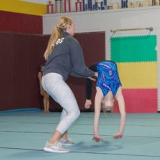 Gymnast receiving assistance during a training session.