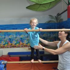 A small girl standing on a pole with her instructor