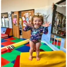 A small girl wearing a cute dress standing on a box