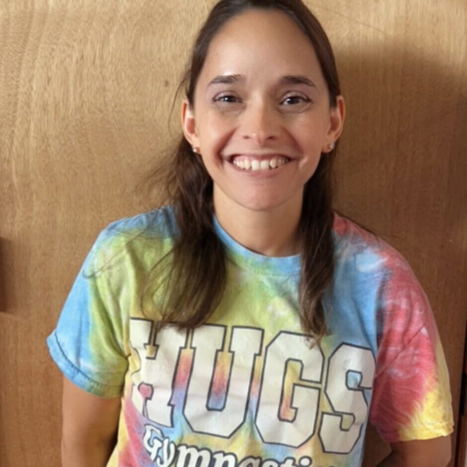 Smiling person in colorful tie-dye shirt.